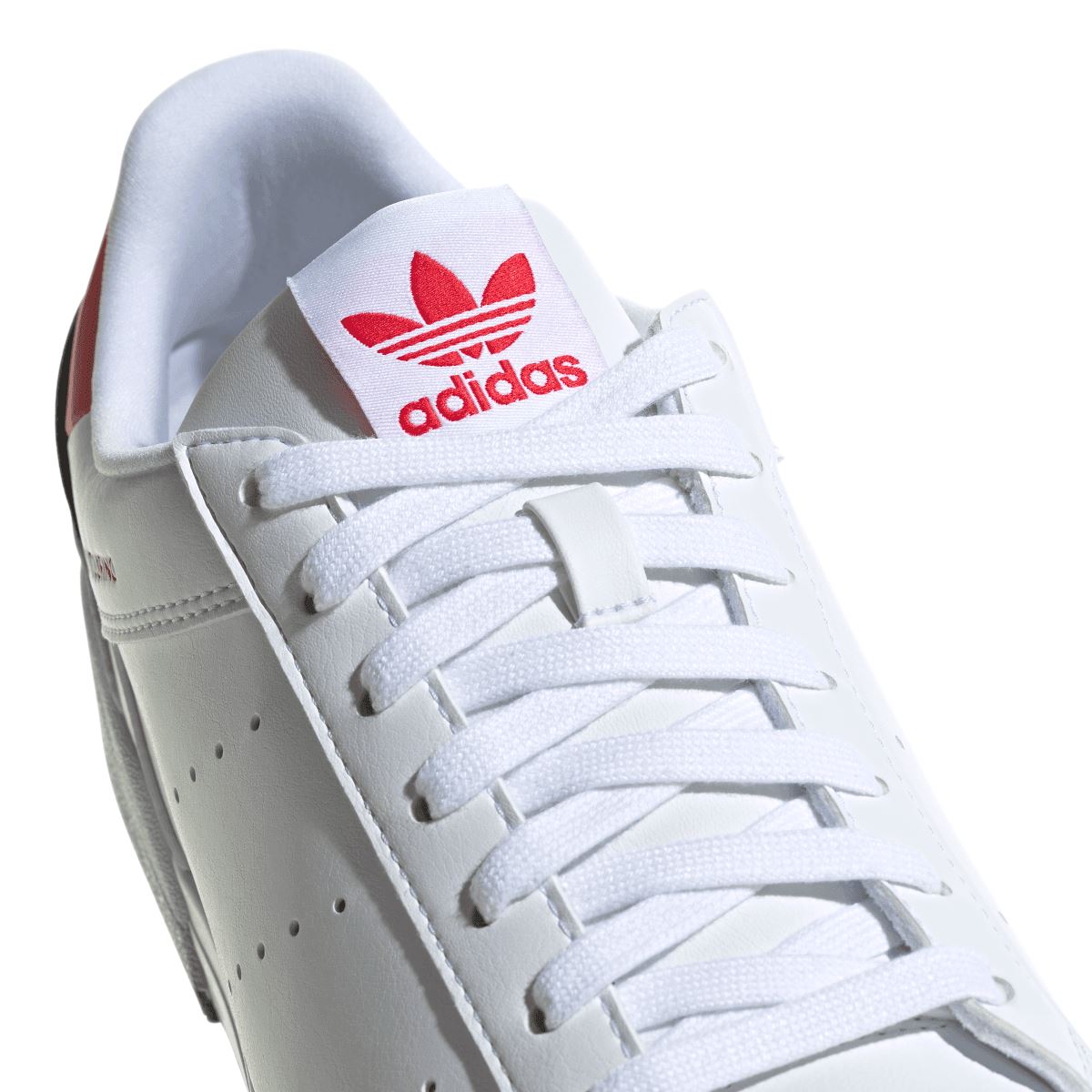 Close-up of white adidas Originals trainers with laces and red adidas Trefoil on tongue