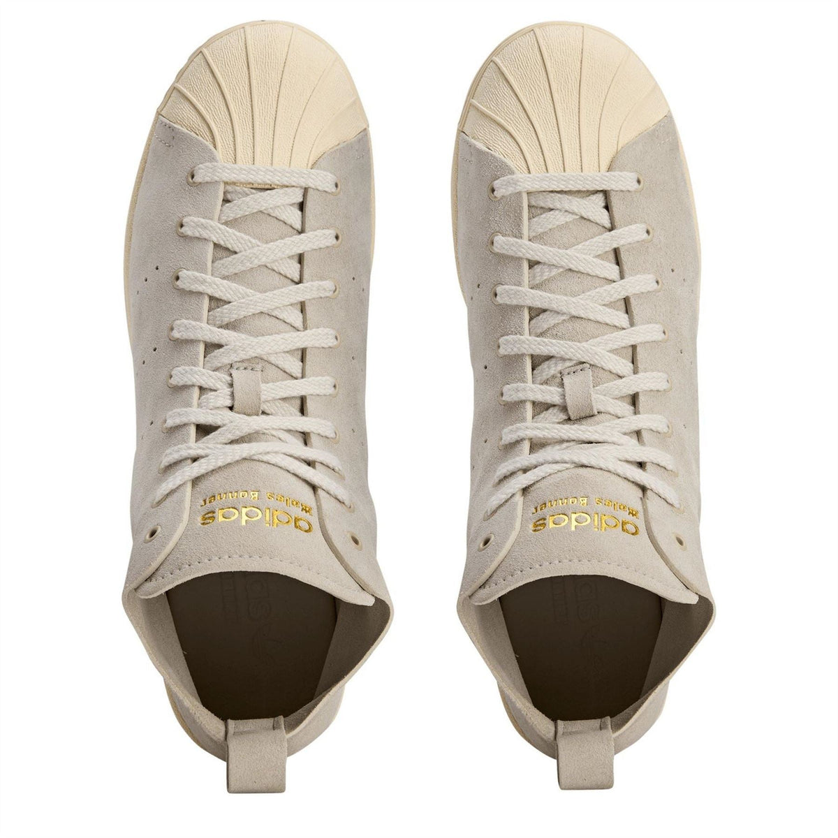 Cream suede sneakers with white laces and adidas logo on tongue, open collar.