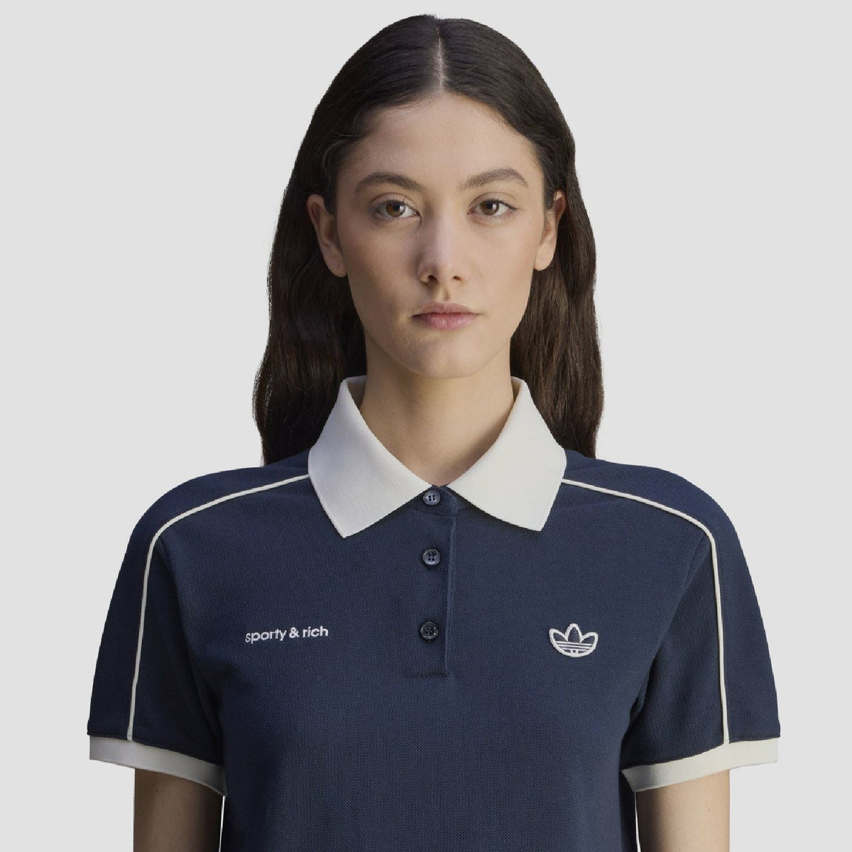 Navy polo shirt close-up with white collar, button placket, and adidas Originals crest