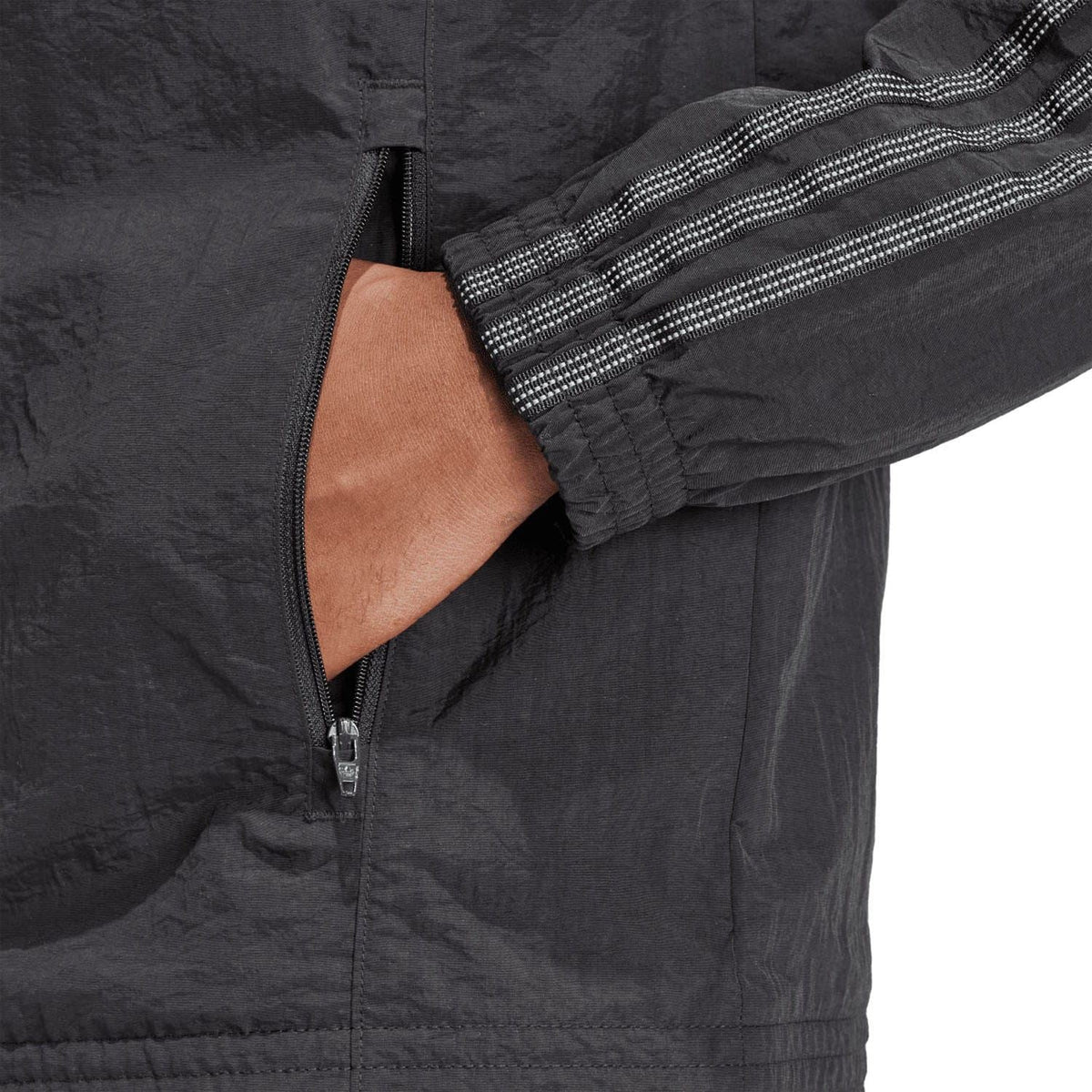 Black zip track jacket detail with mesh-like texture and ribbed hem cuffs.