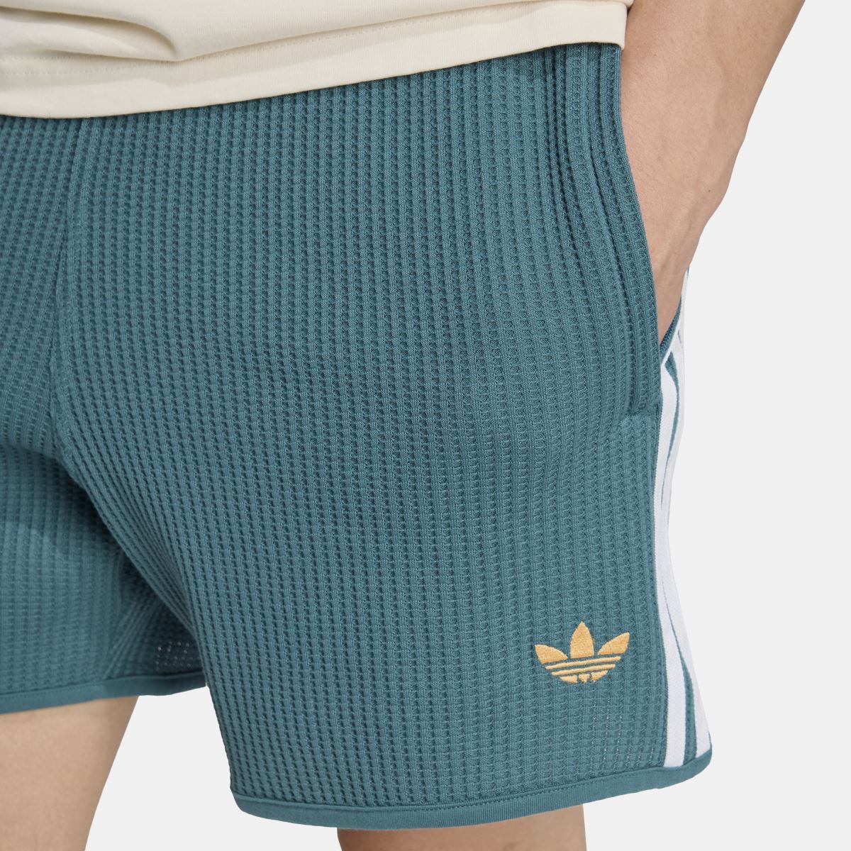 Waffle knit sprinter shorts hem close-up, teal-green with adidas trefoil logo