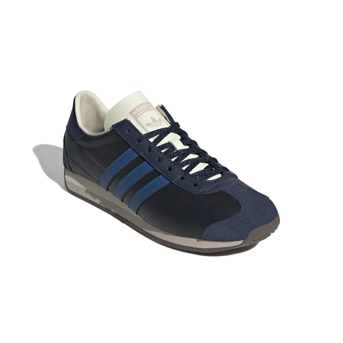Side view of navy/black Country OG trainer with blue stripes, cream lining, and laces