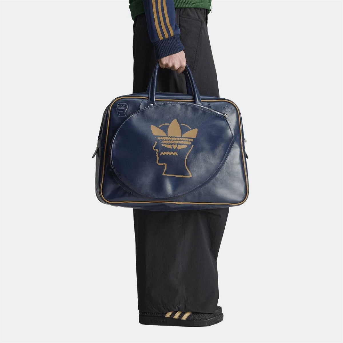 Navy duffel bag with top handles and front gold Trefoil head logo