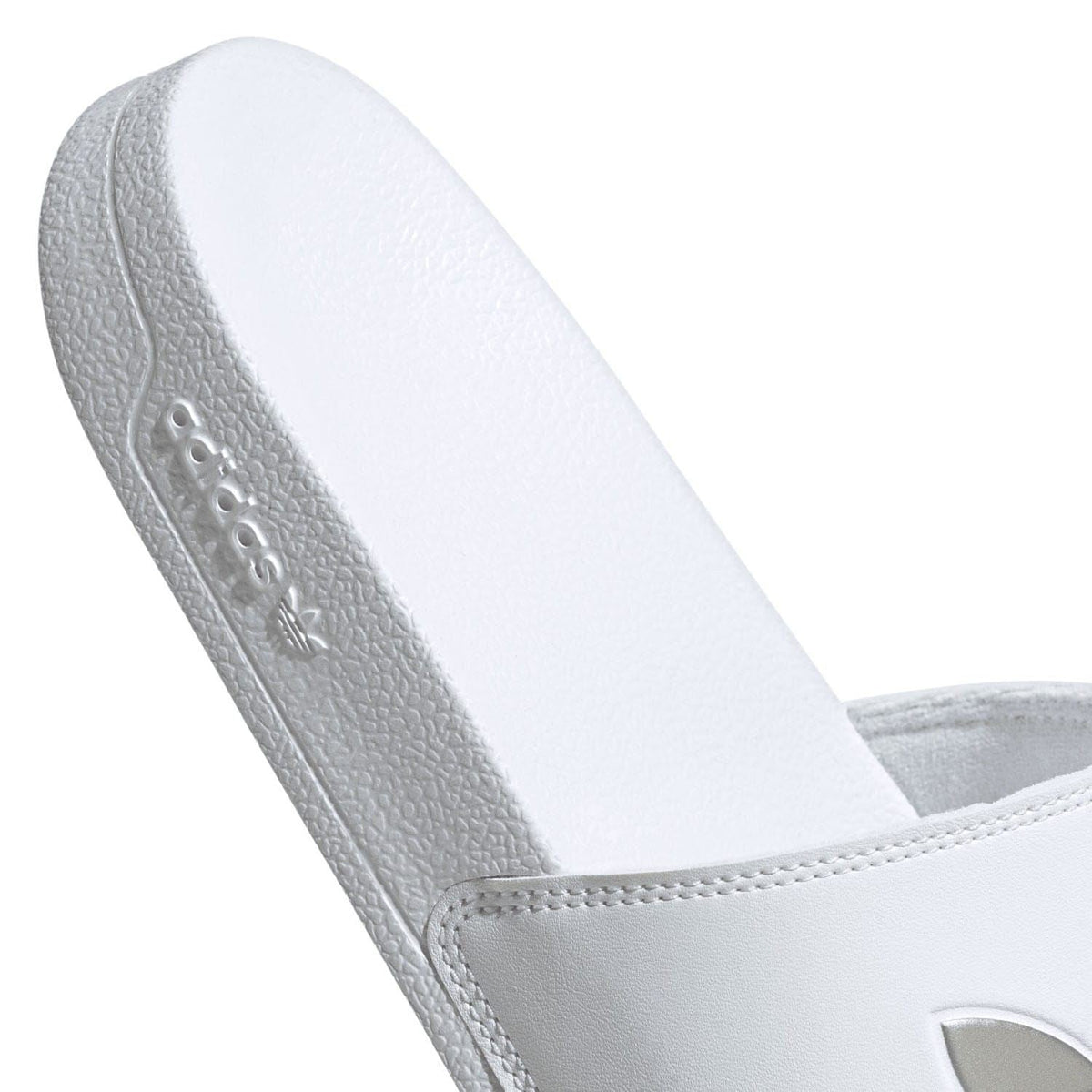 White adidas slide sandal heel and side view with embossed branding on sole