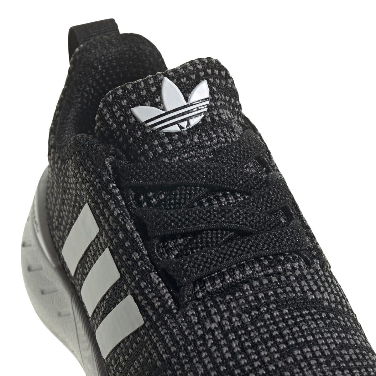 Infant shoe close-up: black knit upper with white stripes and lace detail near tongue