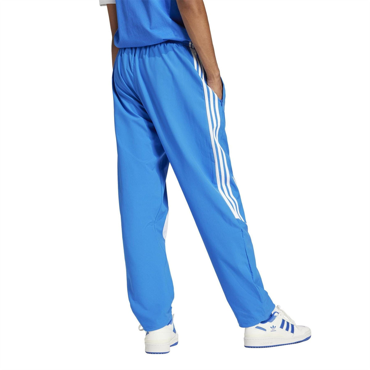 adidas Originals blue track pants with three white stripe panels and tapered fit