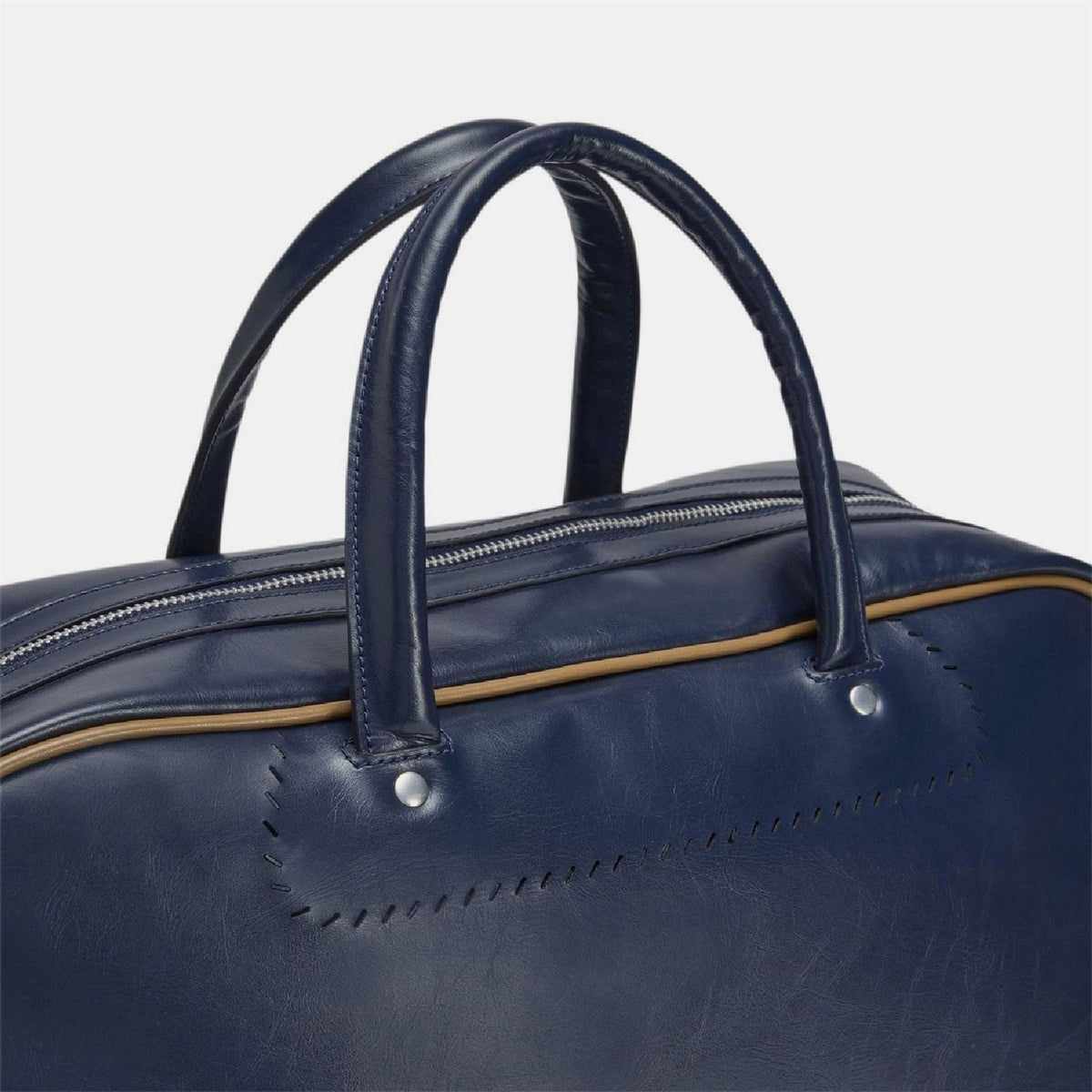 Navy duffel bag close-up of top handles and gold-trimmed zipper edge