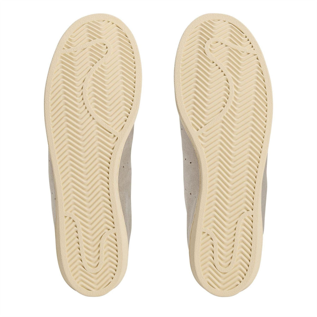 Cream rubber sneaker soles with textured herringbone tread pattern.