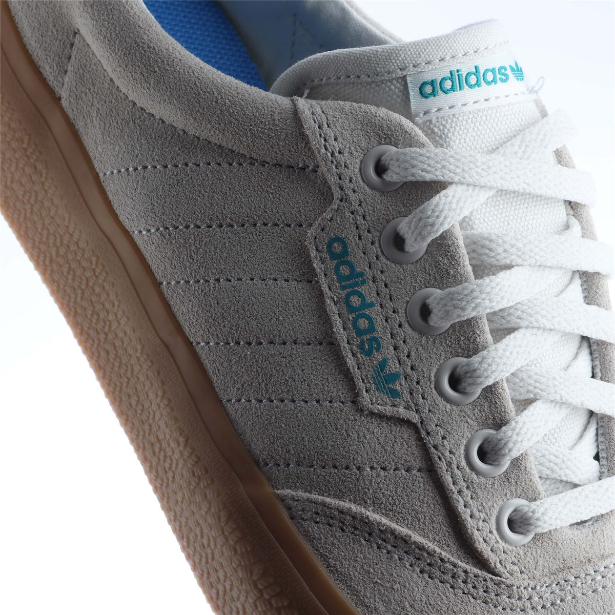 Close-up of white adidas 3MC trainers: side stripe, lace eyelets, and gum sole