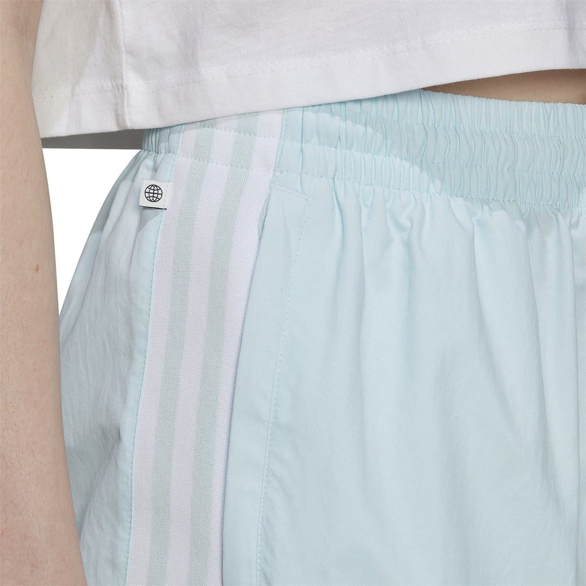 Light blue sweatpants close-up with elastic waistband and side logo patch