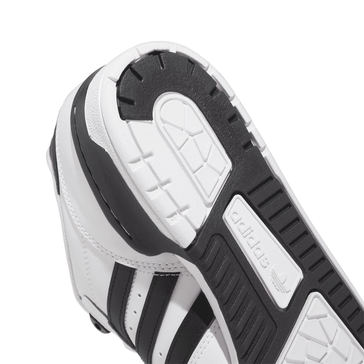 White low-top trainers bottom view with treaded outsole and black forefoot panels