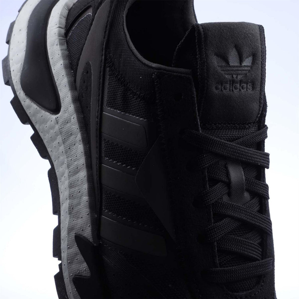 Black trainers detail: lace-up eyelets, padded heel, and adidas logo tab