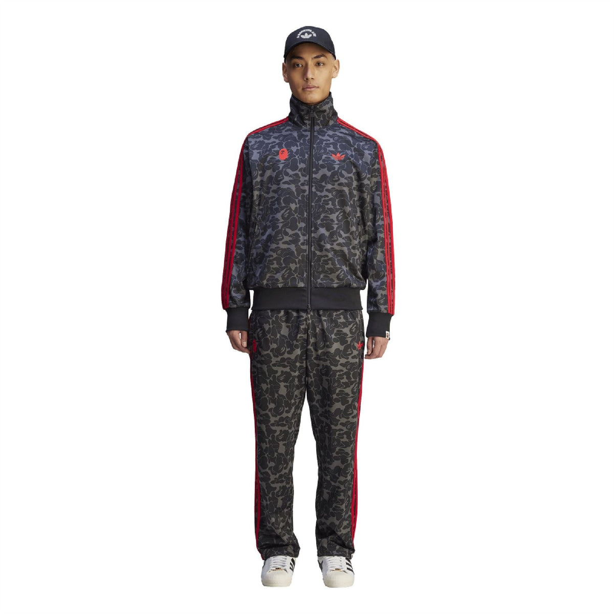 Camo trackpants with red side stripes, elastic waistband, and tapered cuffs.