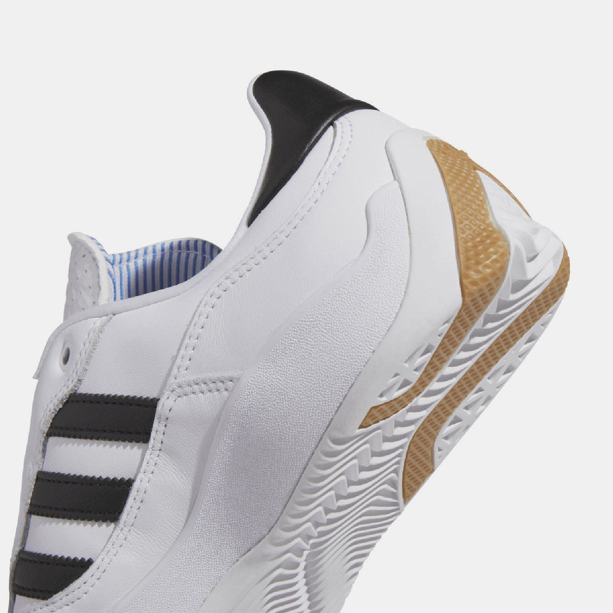 Close-up of white leather upper with black stripes and brown tread detail