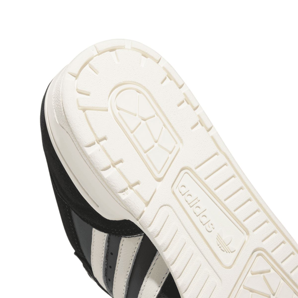 Close-up of white outsole tread with molded geometric pattern and branding panel
