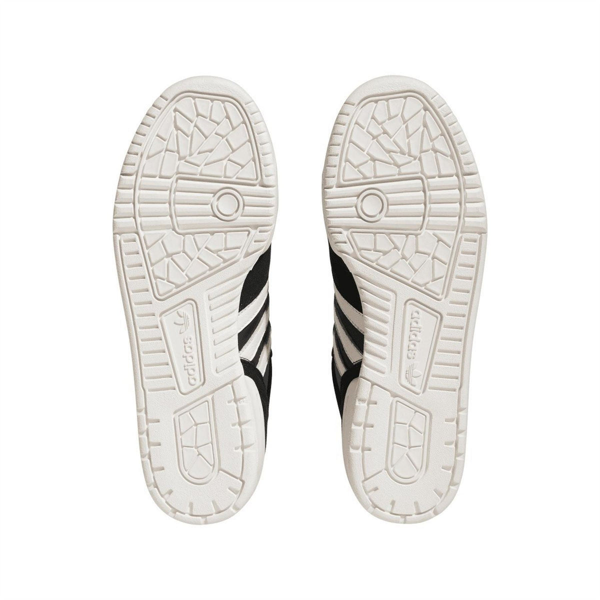 Underside of black-and-white low-top trainers showing tread pattern