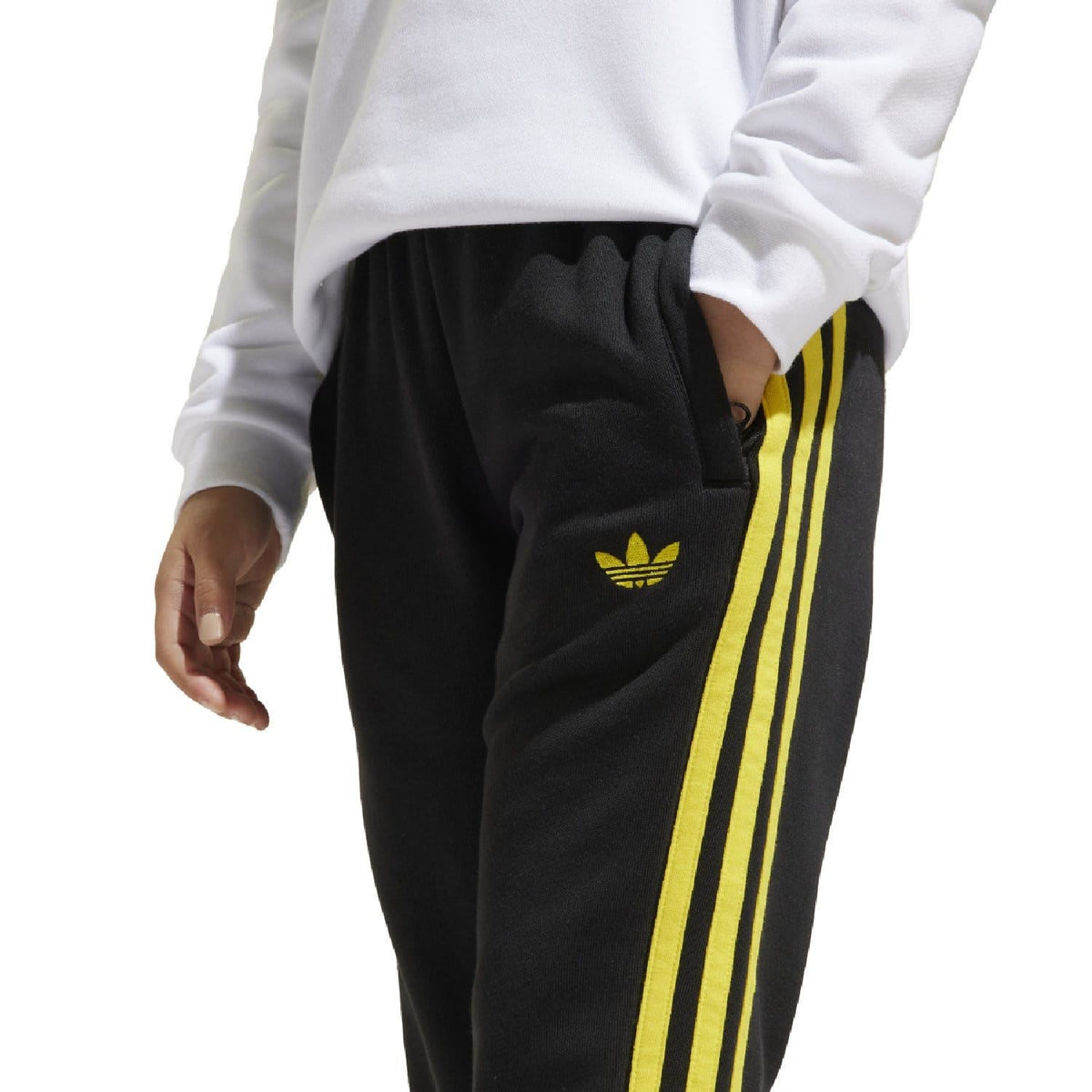 Black kids joggers with yellow side stripes and small yellow adidas trefoil on thigh.
