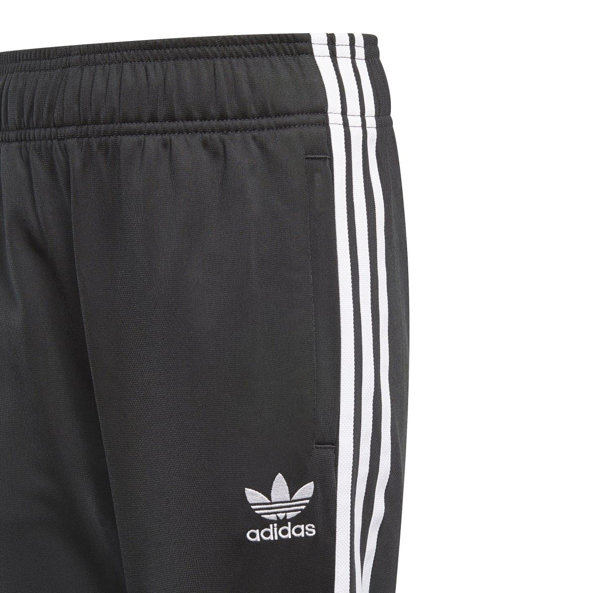 Black junior track pants waistband close-up with adidas trefoil and white triple stripes