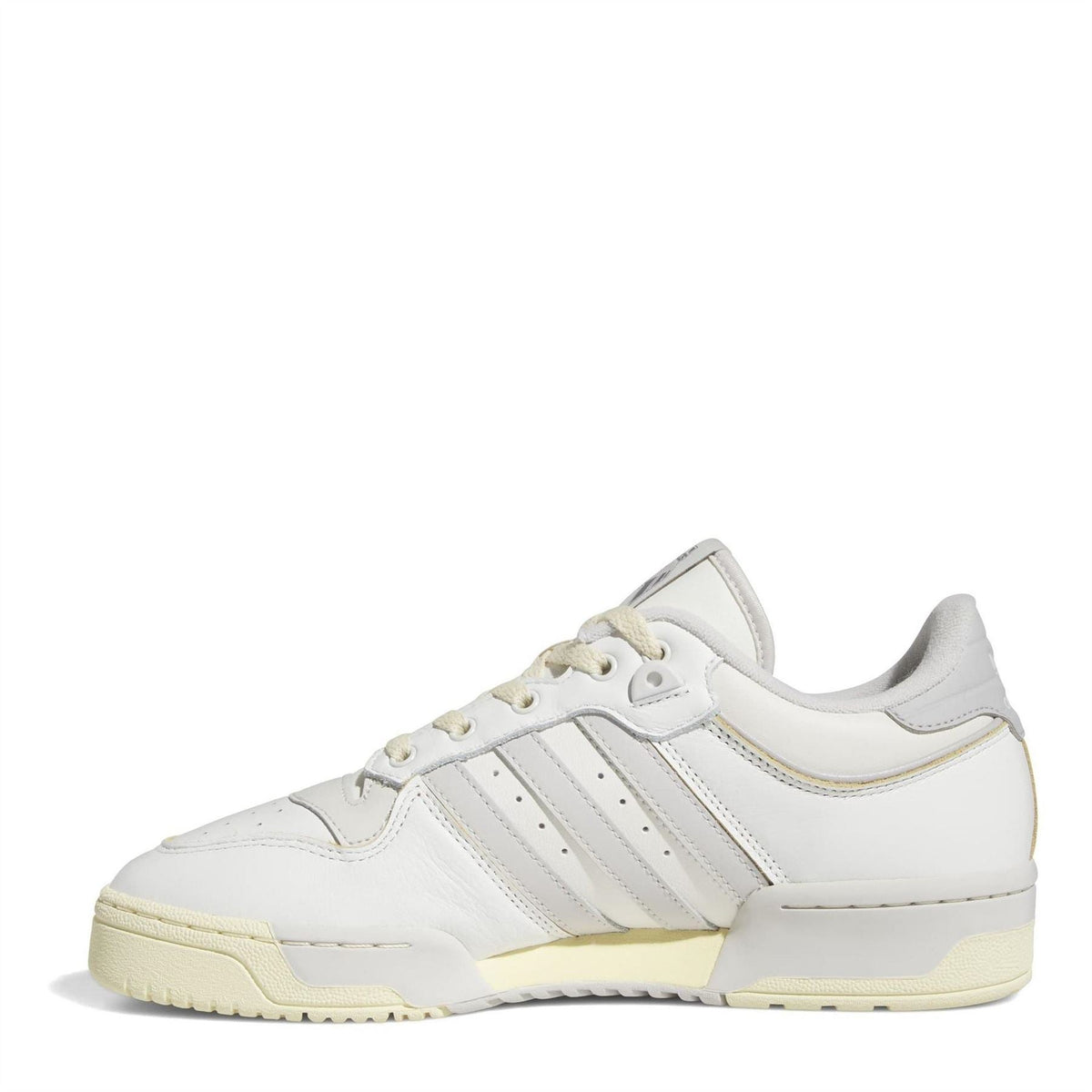 White low-top trainers with three stripes, lace-up closure, and light gum rubber sole.