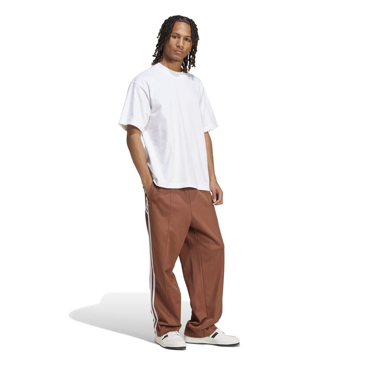 Brown baggy track pants with white triple side stripes, elastic cuffs, adidas logo