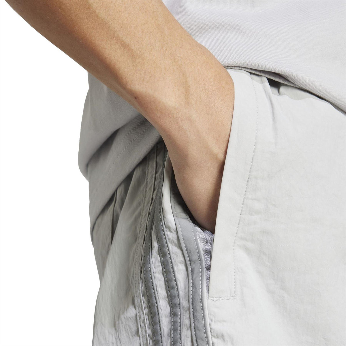 Light grey shorts fabric close-up showing pleats and seam near the pocket