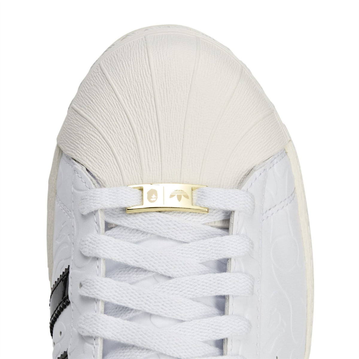 White sneaker upper with lace-up detail and gold crossbar hardware