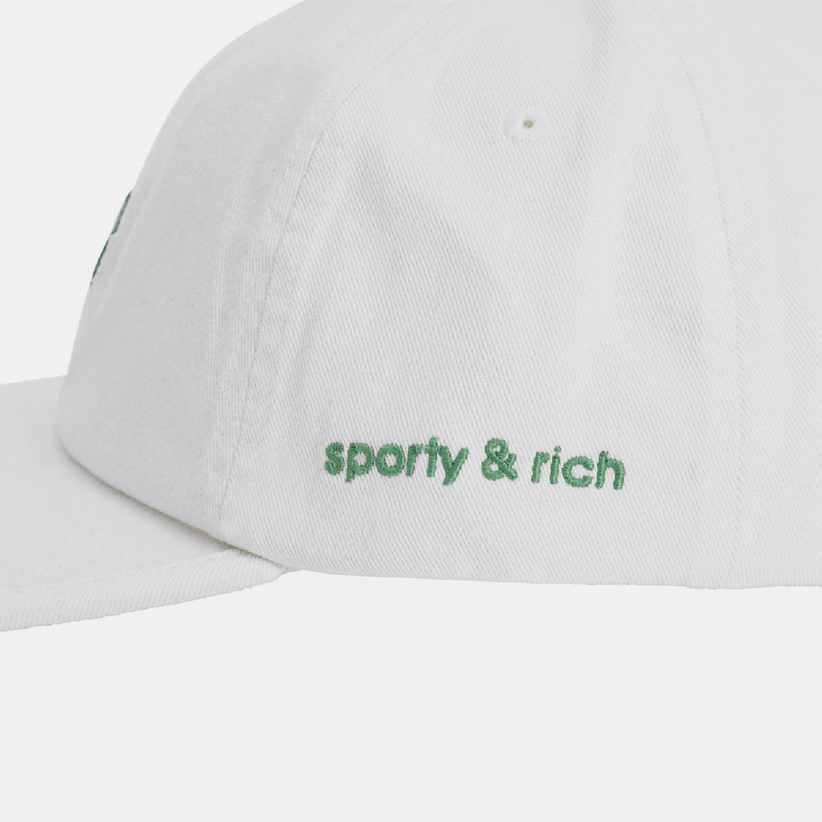 White cap close-up with green 'sporty & rich' logo on front panel