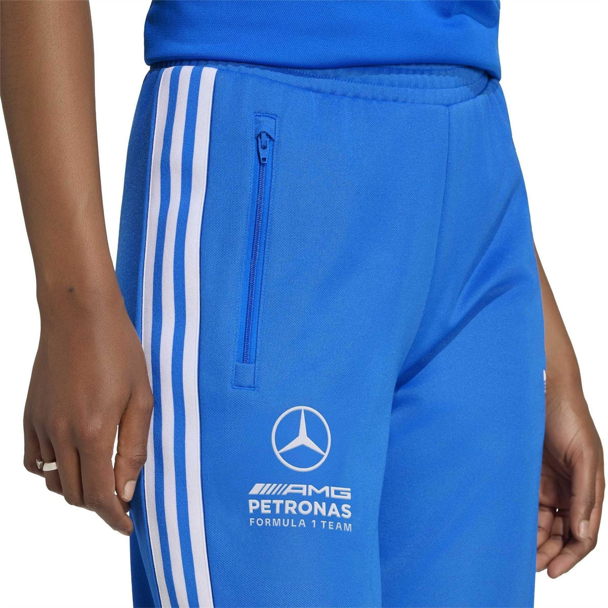 Blue track pants with ribbed waistband, zip pocket, and white side stripes.