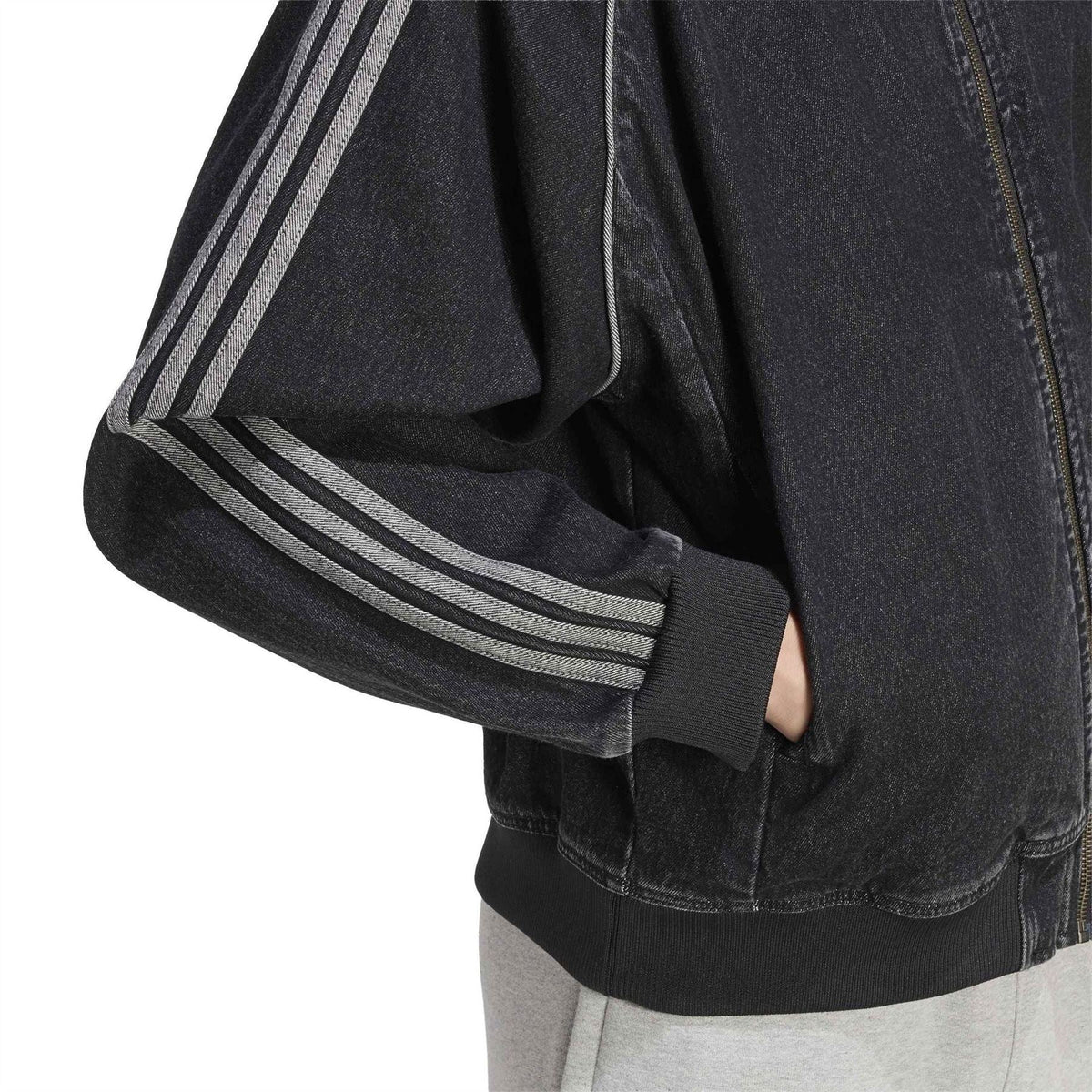 Black denim bomber jacket sleeve with three stripe detailing and ribbed cuff.