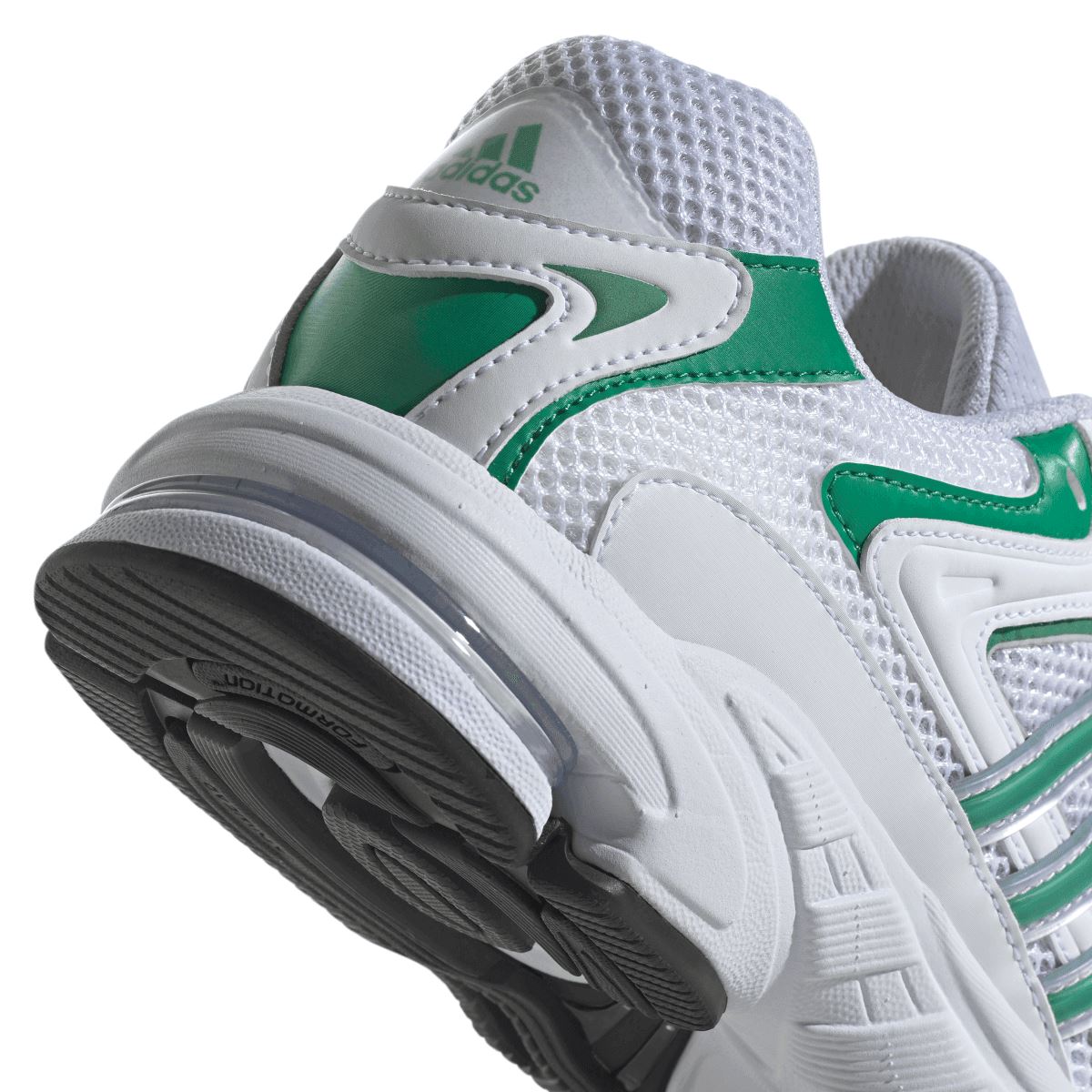 Close-up of white trainer side with green swoosh panel and black outsole tread
