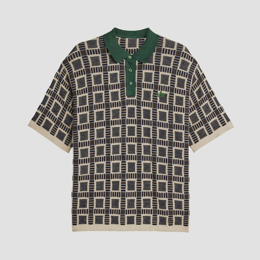 Sand polo shirt with green collar and button placket; navy-and-cream grid pattern.