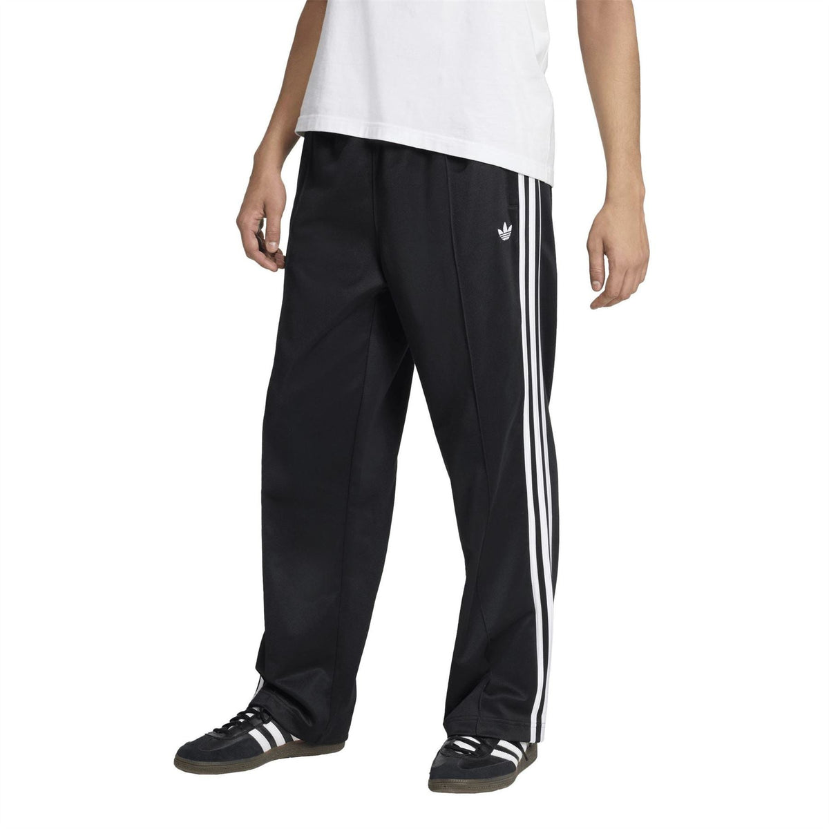 Black track pants with white side stripes, trefoil logo, relaxed leg and cuffed hem