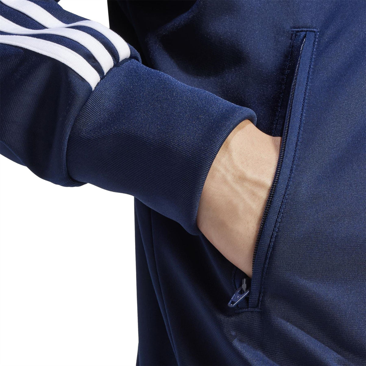 Men's indigo track jacket sleeve close-up with ribbed cuff and zip pocket detail