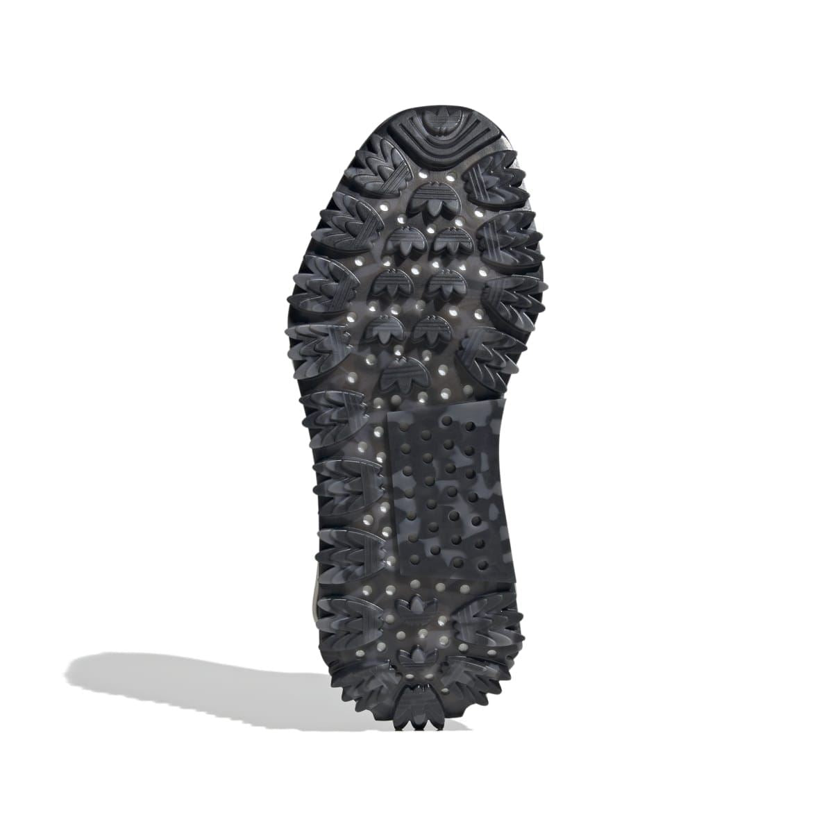 Black outsole of lace-up trainer with traction pods and raised tread pattern