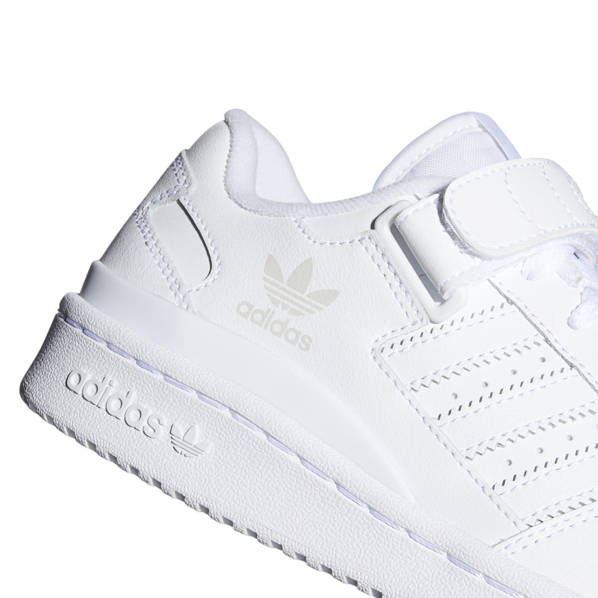 White kids low-top trainer close-up of side panel, adidas logo, and three stripes