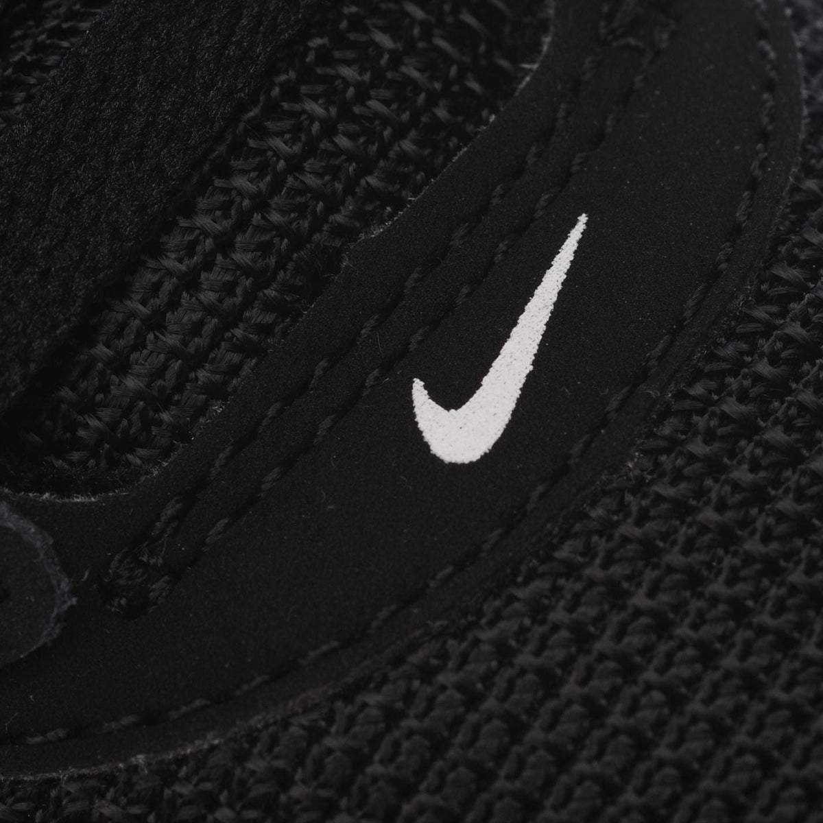 Black boys' Nike trainers close-up with white swoosh and textured upper