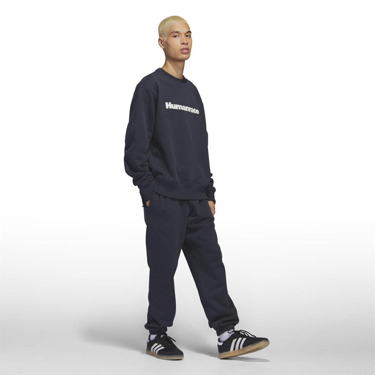 Dark navy crewneck sweatshirt with “Humanrace” logo; model wearing matching joggers.