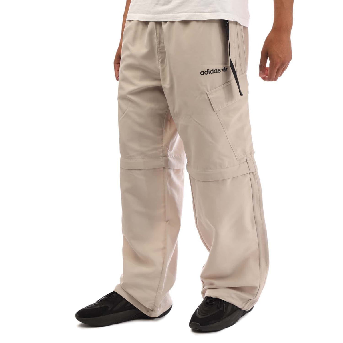 Beige zip-off jogger pants with adidas logo, side pockets, and zip-off legs