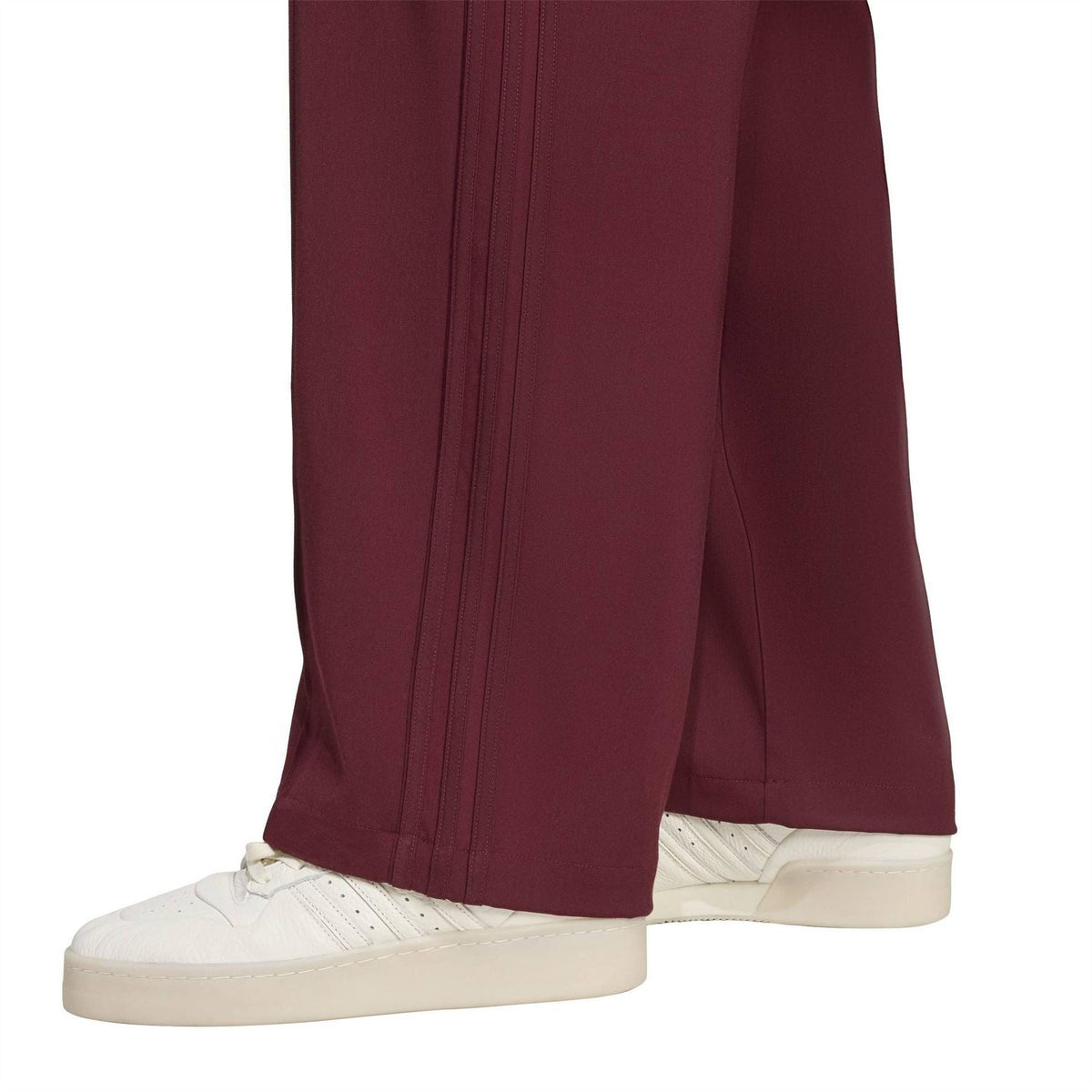 Maroon track pants showing side seam details and tapered hem over white sneakers