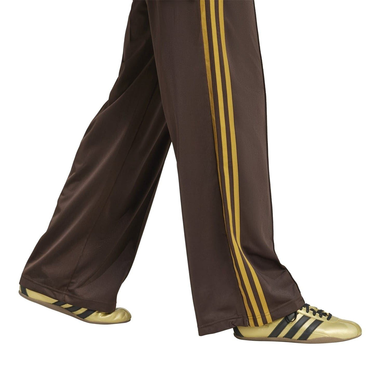 Brown wide-leg track pants with gold side stripes and Adidas trefoil detail