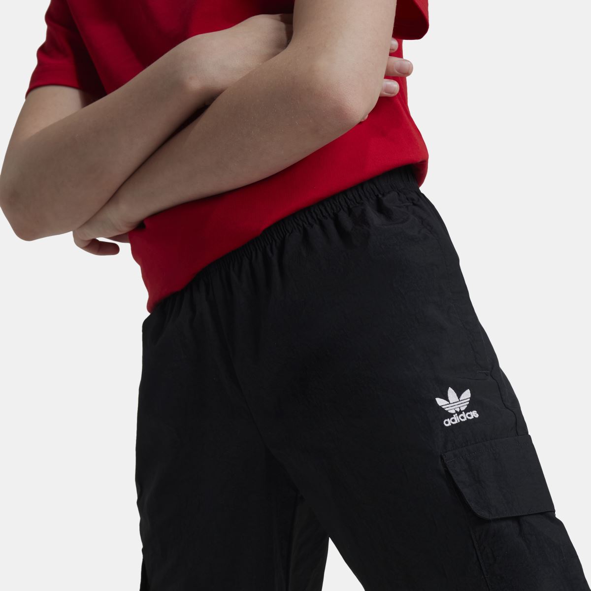 Kids black cargo track pants close-up with elastic waistband, adidas trefoil, and cargo pocket
