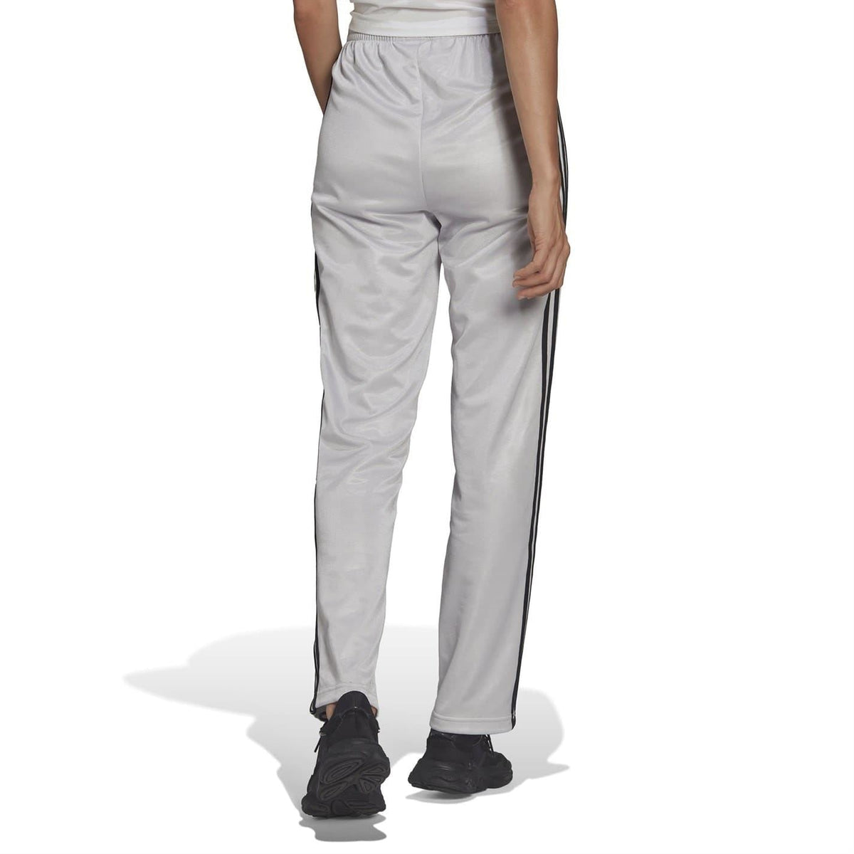 Light gray adidas Originals sweatpants with black side stripes, tapered leg