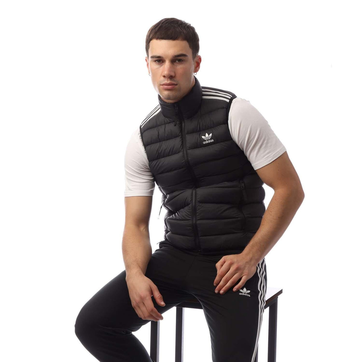 Black padded puffer vest with stand-up collar, adidas logo, and three-stripe shoulder detail