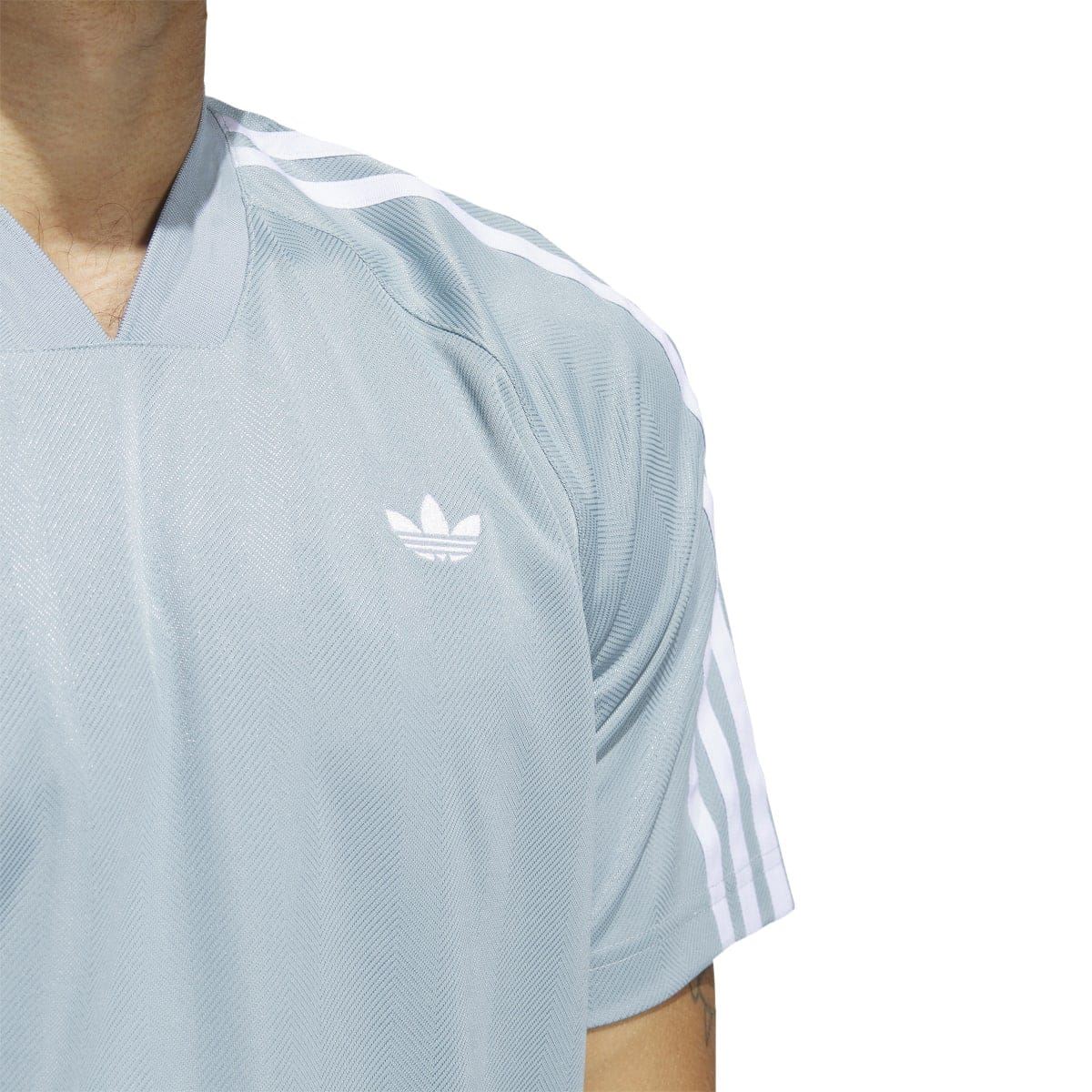 Close-up of light blue jersey T-shirt chest logo and three adidas shoulder stripes