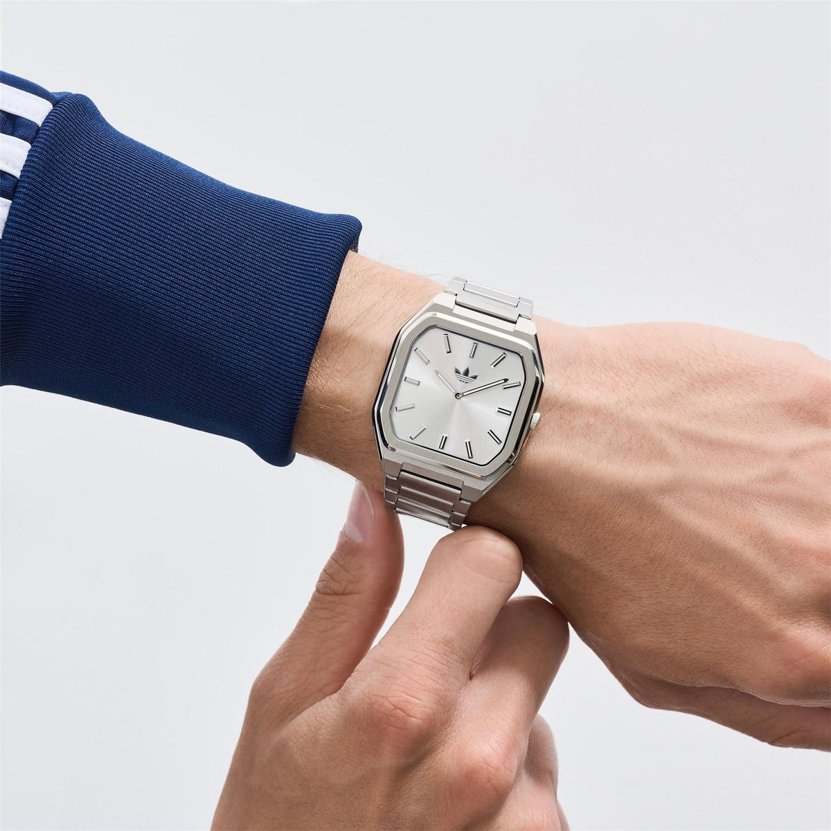 Silver analog watch on wrist with metal link bracelet and square dial