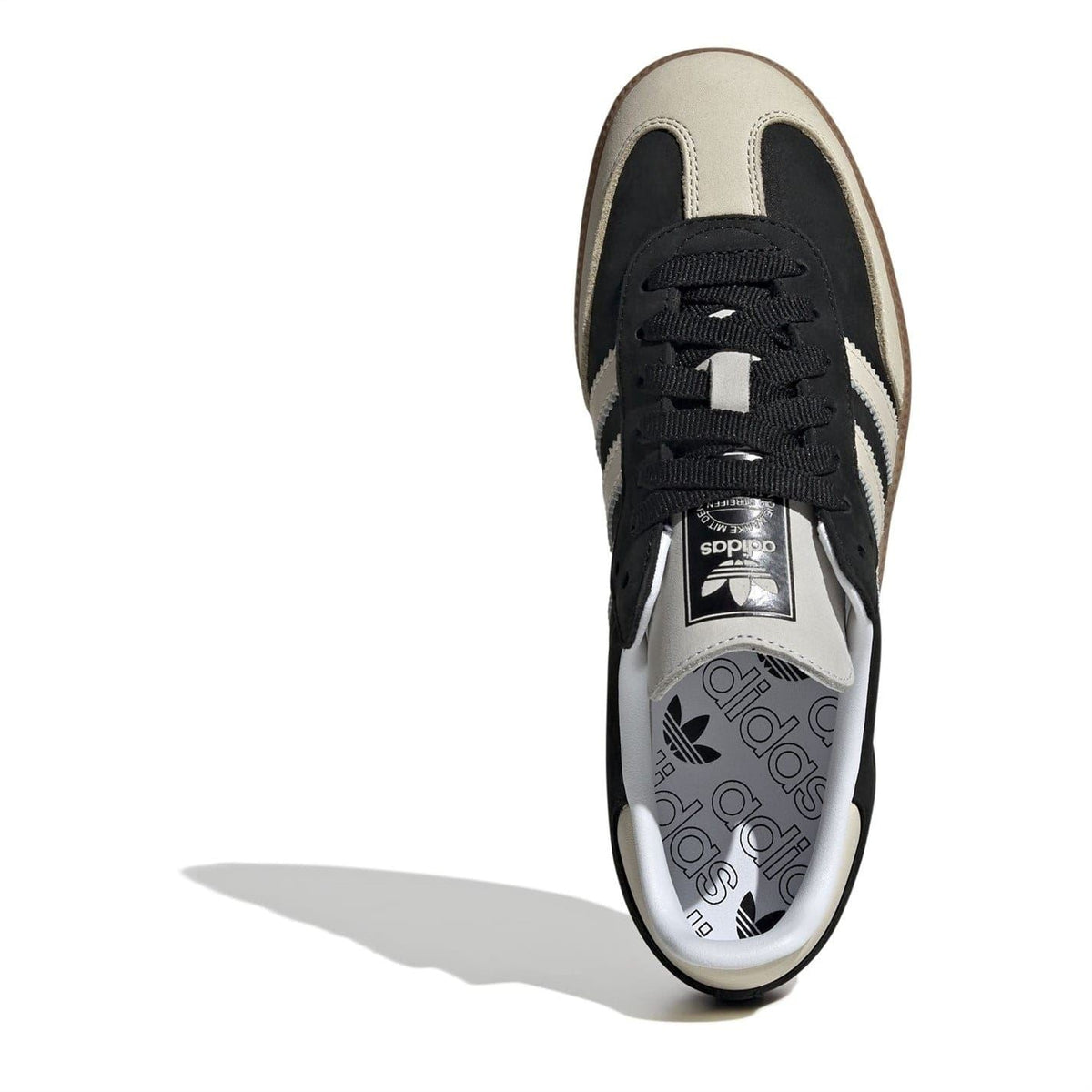 Sneaker upper close-up with black laces, beige toe, and adidas tongue label