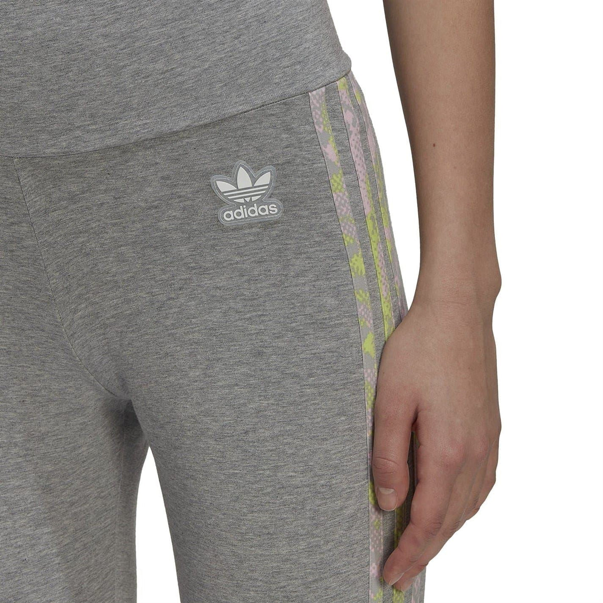 Close-up of grey leggings showing adidas trefoil logo and pastel side stripe trim