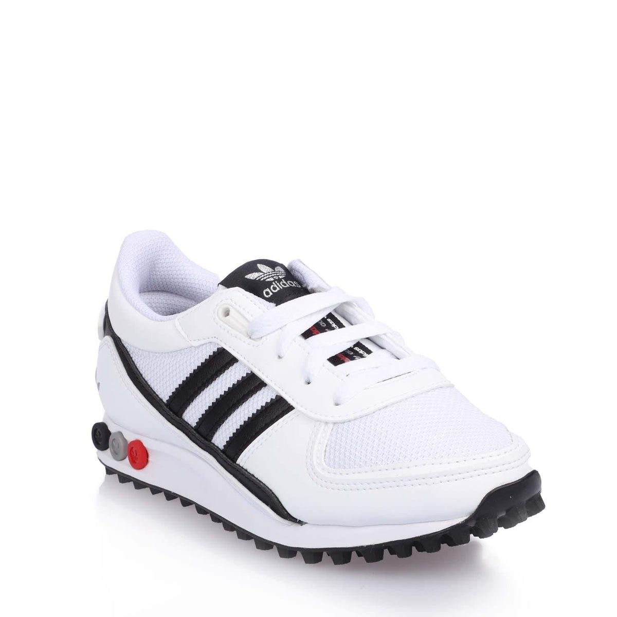 White junior Adidas sneakers with black side stripes, red heel tab, rugged tread.