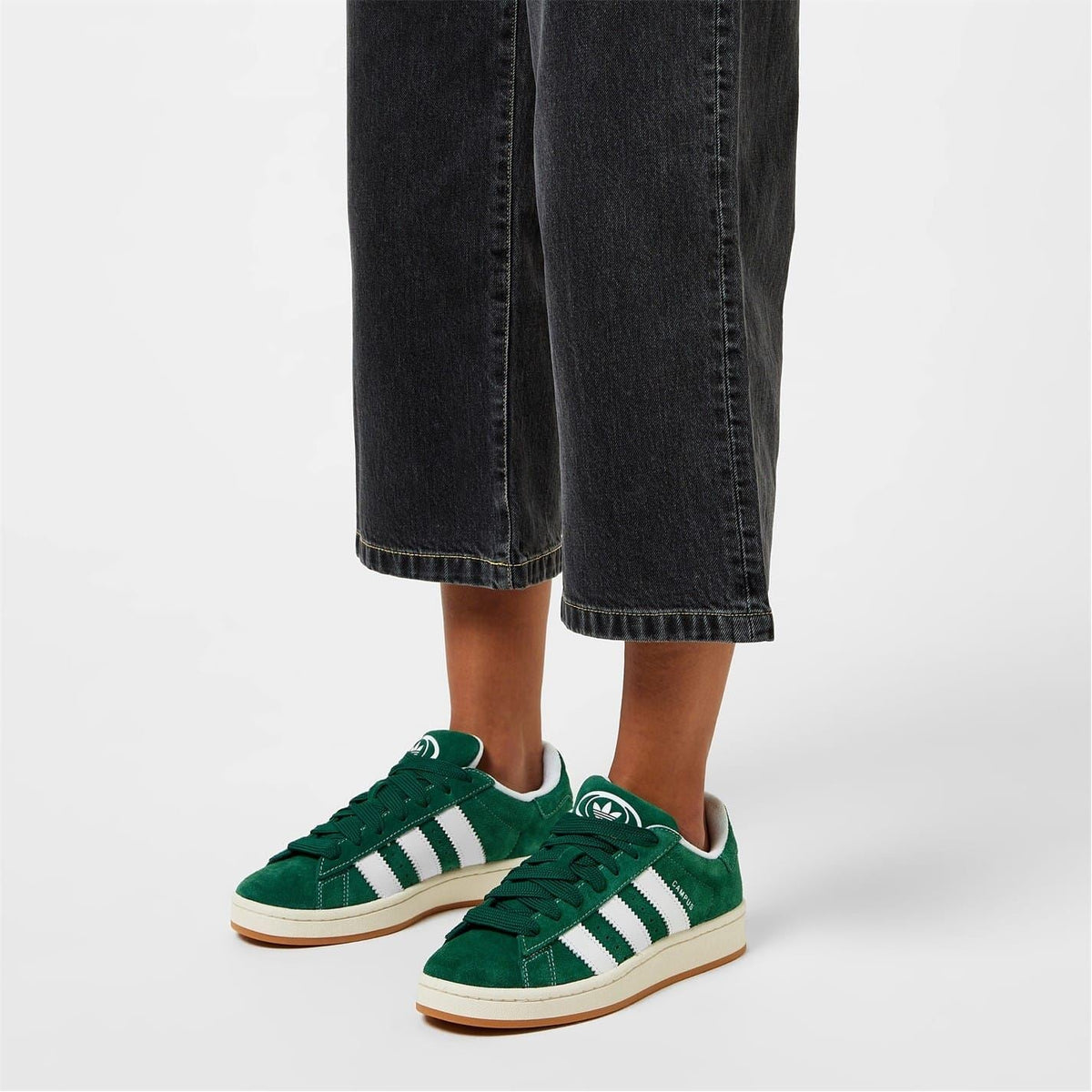 adidas Campus trainers on feet with dark green uppers and white adidas stripes