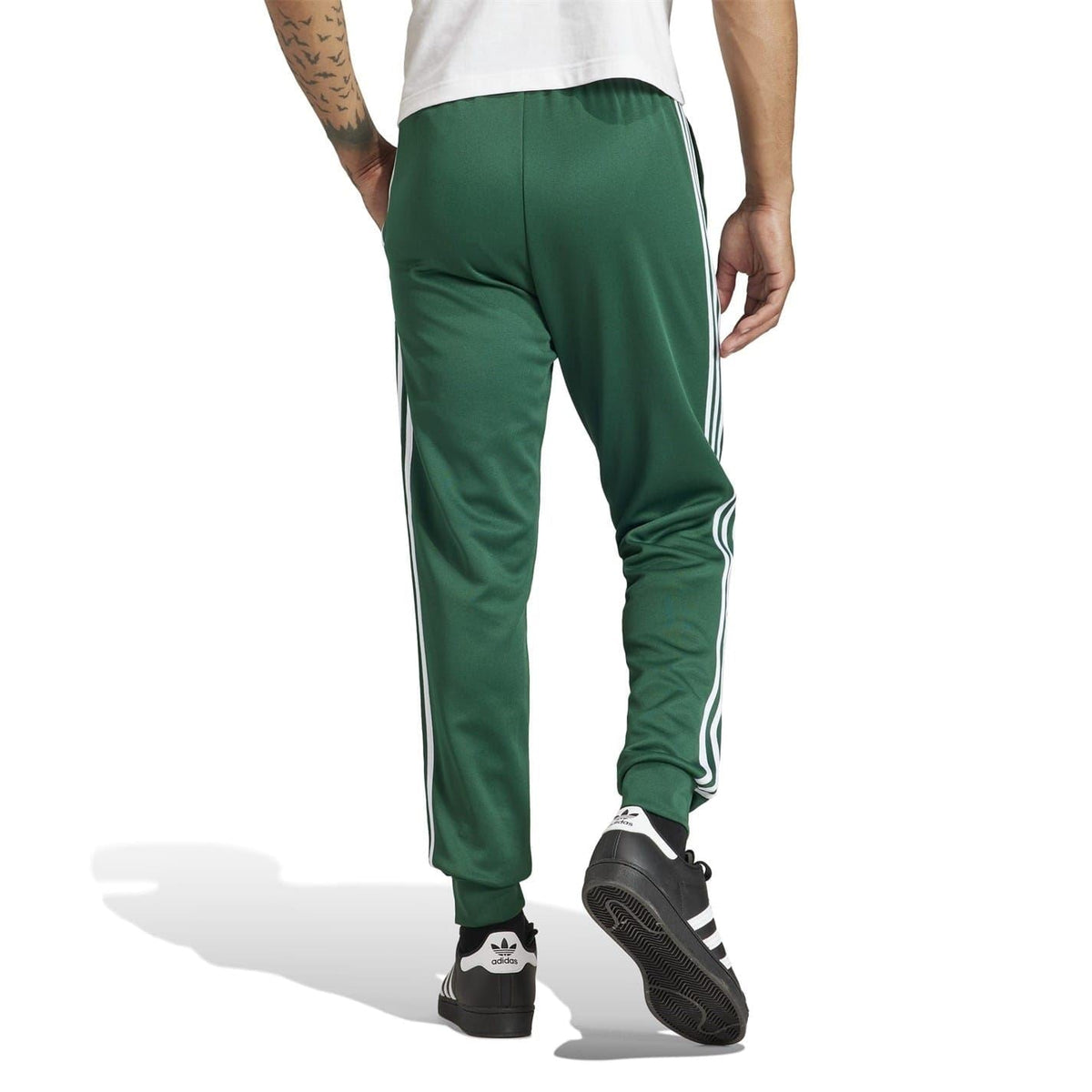 Green track pants with white side stripes, slim fit, ribbed cuffs at ankle